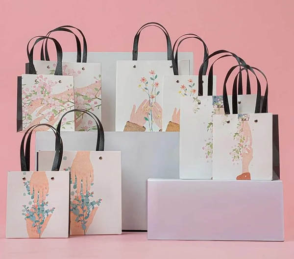 Mẫu túi giấy mỹ phẩm nổi bật với các họa tiết hoa lá cùng bàn tay nâng niu ý nghĩa
